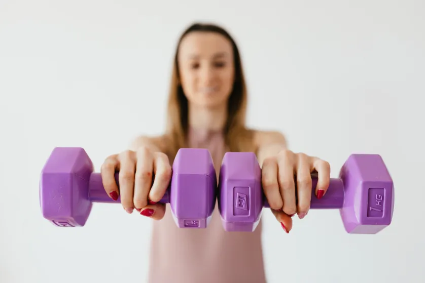 the girl holds dumbbells in front of her